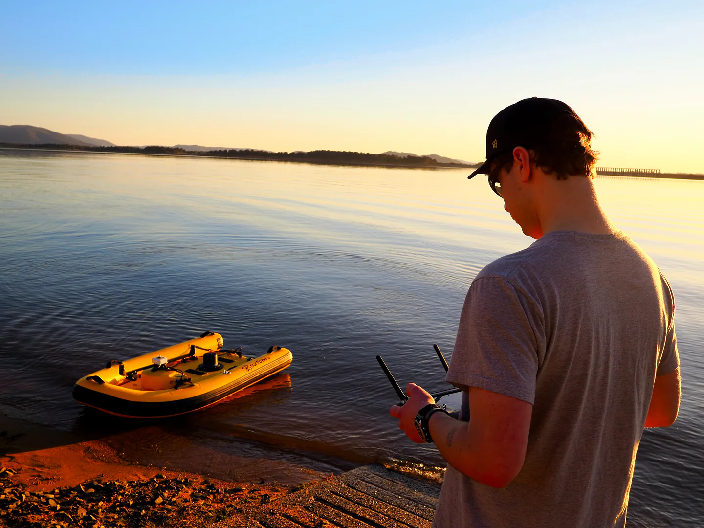 A Surfbee operator steering a vessel from the Lake Hume shoreline